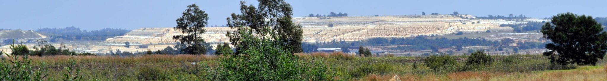 Distant view of a large open-cast mine with terraced, pale earth layers